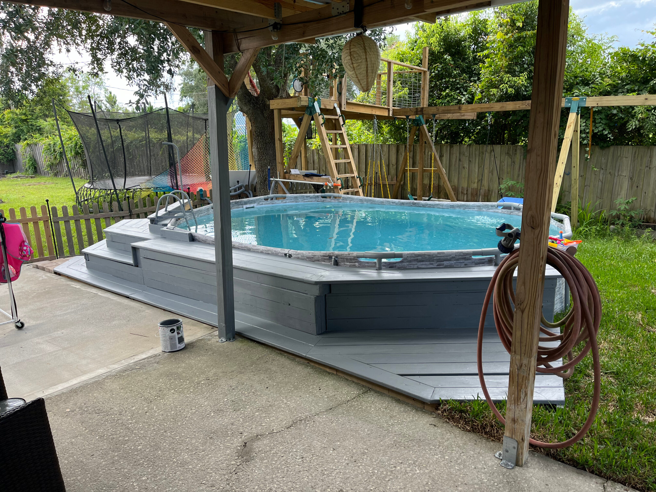 Above-ground pool with custom gray deck and backyard playset installed by Tobinator Services in Central Florida